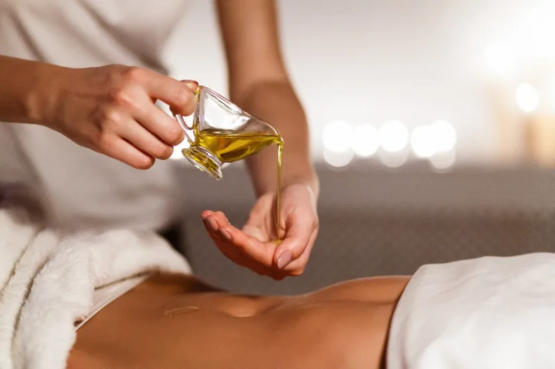 Warm aromatherapy oil poured into the therapist's hand