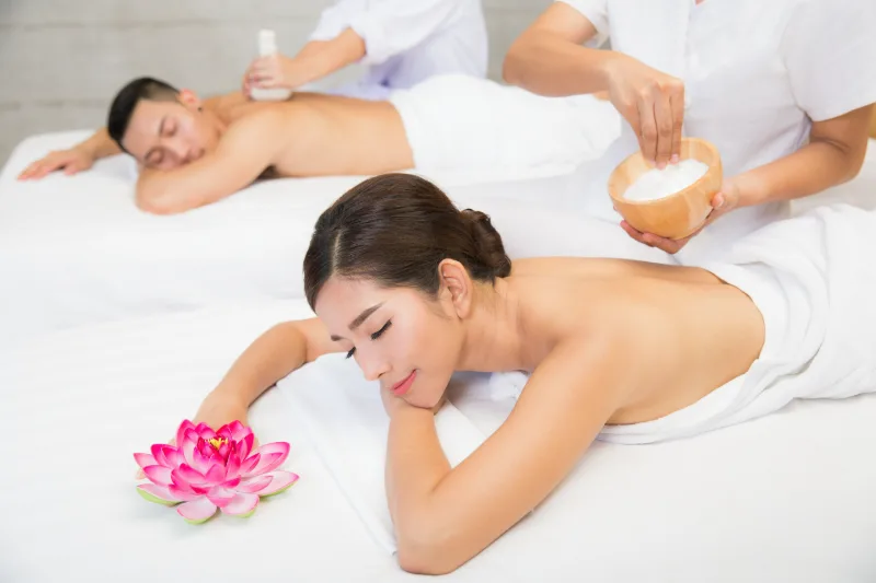 Two clients side by side receiving a couples massage from two therapists