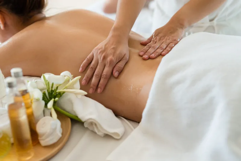 Therapist working oil along the lower back during a deep tissue massage