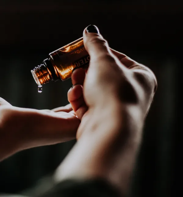 Warm massage oil poured from a bottle into the therapist's hand
